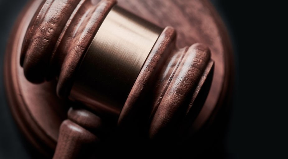 Close-up of a wooden gavel, resting with a brass band visible, set against a dark background, conveying authority and justice.